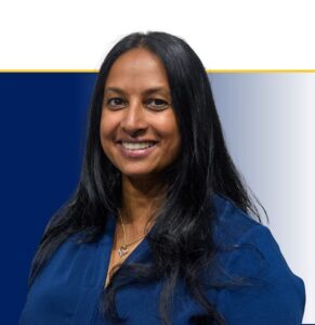 Professional headshot of smiling woman with long black hair wearing dark blue top against blue and white background