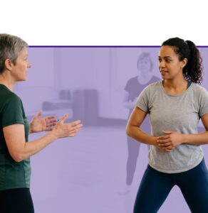 Two women engaged in conversation during a workplace wellness activity with purple background