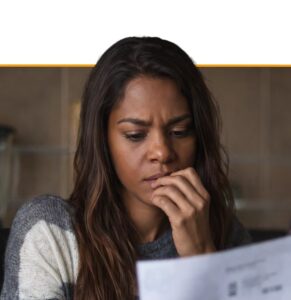 Woman in contemplative pose reviewing documents, representing engagement with workplace wellbeing resources