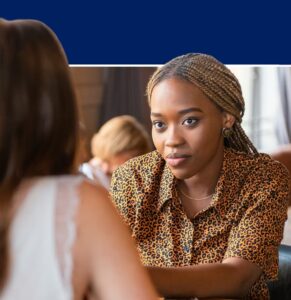 Two women in conversation during a workplace wellness session, one wearing a leopard print shirt engaging attentively with the other