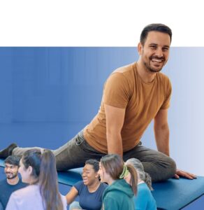Instructor smiling while leading a fitness class for a diverse group of participants on exercise mats